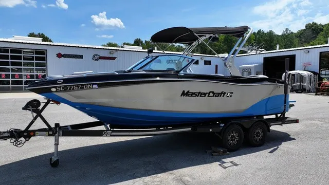 Slide: The Image of A 2019 MasterCraft XT22 boat on a trailer in front of a building. - 7