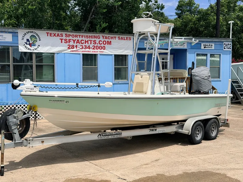 The Image of A 2013 Pathfinder 2400 boat on a trailer in front of a blue building with a sales banner. - 1