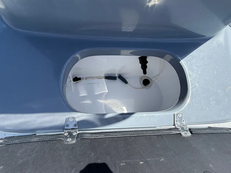 Slide: The Image of An open storage compartment on a boat with a gray lid and hinges. - 18