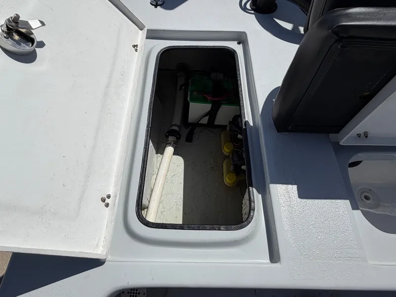 Slide: The Image of An open storage compartment on a boat with visible pipes and a battery. - 28