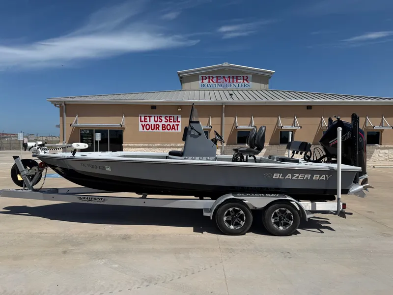The Image of A gray 2023 Blazer Bay 2220 GTS boat on a trailer in front of a building. - 1