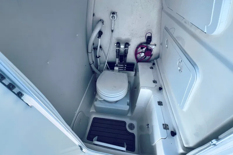 Slide: The Image of Interior of 2021 Tidewater 256 CC Adventure boat featuring compact marine toilet setup. - 25