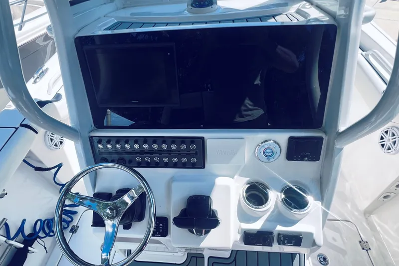 Slide: The Image of 2021 Tidewater 256 CC Adventure boat dashboard with steering wheel and control panel. - 26