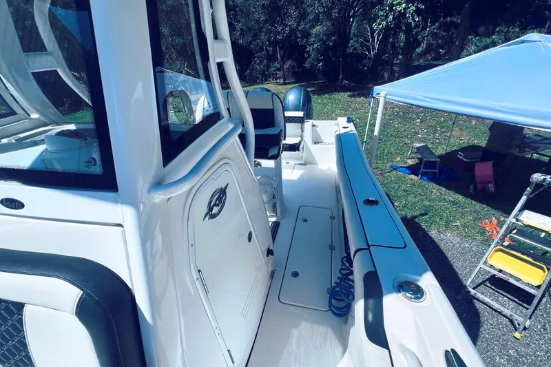 Slide: The Image of 2021 Tidewater 256 CC Adventure boat, white interior, parked outdoors under a canopy. - 18