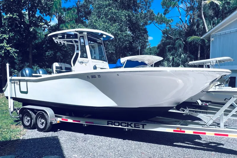Slide: The Image of 2021 Tidewater 256 CC Adventure boat on trailer, surrounded by trees. - 33