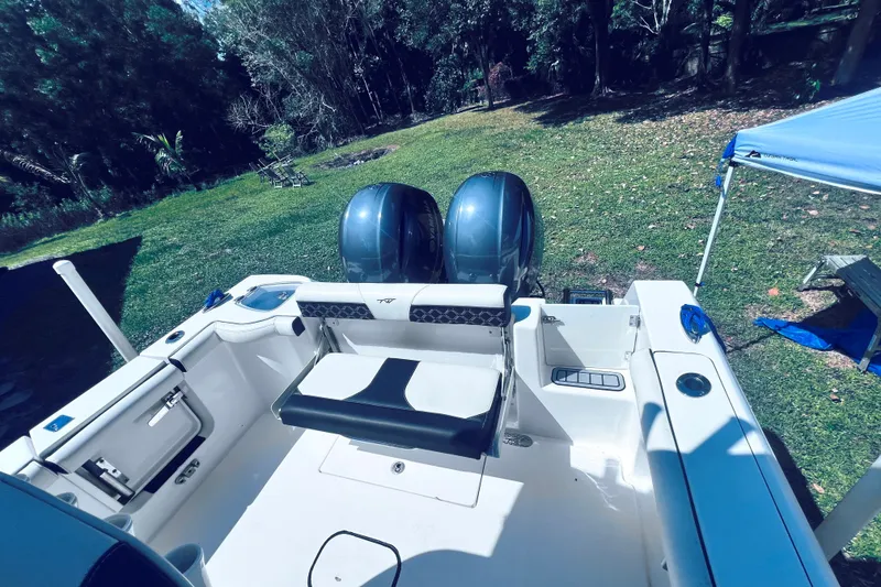 Slide: The Image of 2021 Tidewater 256 CC Adventure boat with dual engines, parked on grassy area. - 10