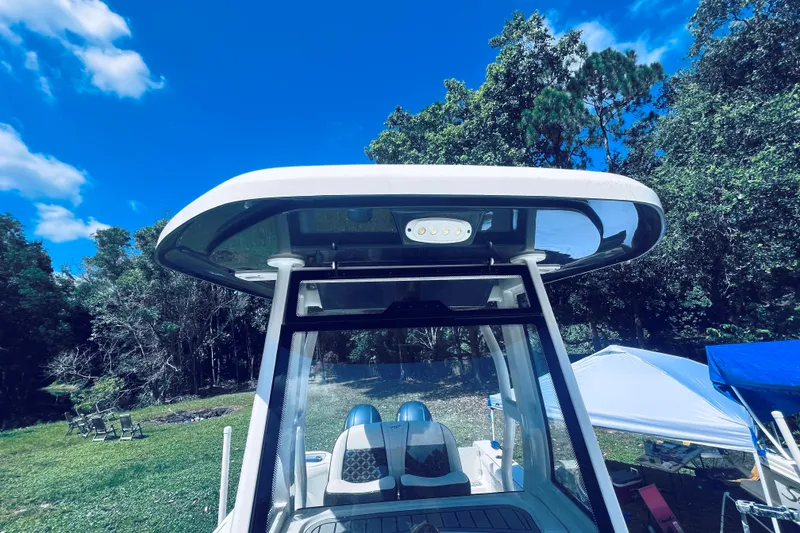 Slide: The Image of 2021 Tidewater 256 CC Adventure boat with T-top, set against a lush, green backdrop. - 21