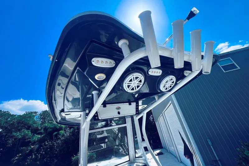 Slide: The Image of 2021 Tidewater 256 CC Adventure boat with rod holders and speakers under a clear blue sky. - 12