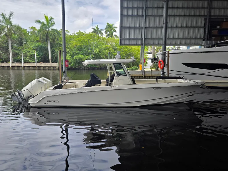 The Image of A 2024 Boston Whaler 330 is docked in the water under a covered dock. - 0