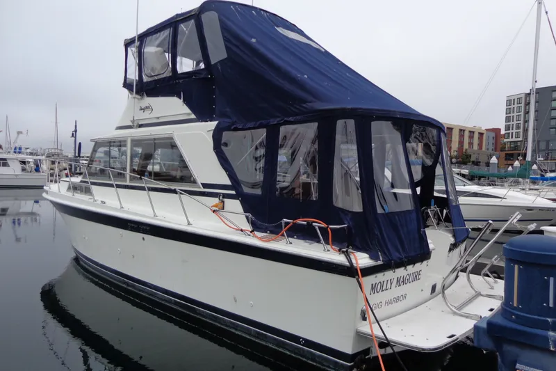 Slide: The Image of 1975 Uniflite Flybridge Sport Sedan docked, featuring blue canopy and sleek design. - 5