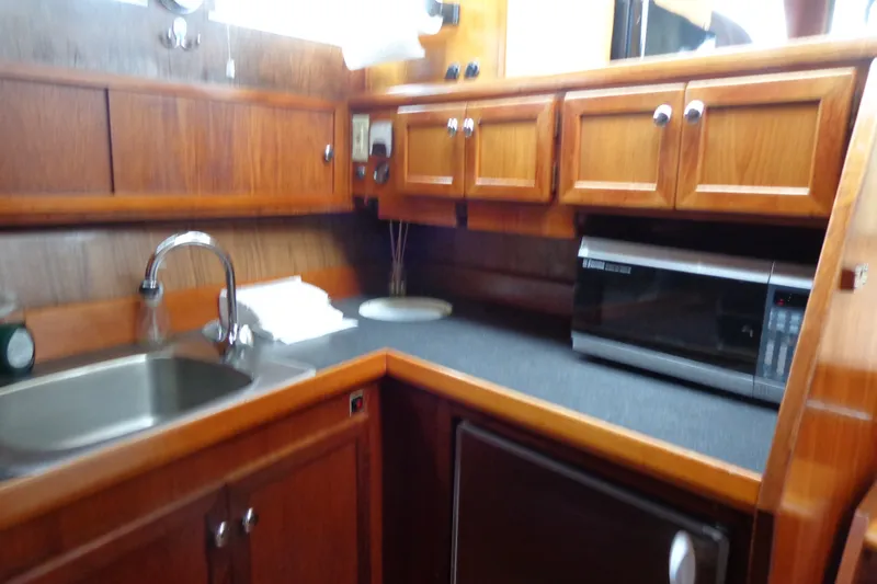 Slide: The Image of 1975 Uniflite Flybridge Sport Sedan kitchen with wooden cabinets and modern appliances. - 12