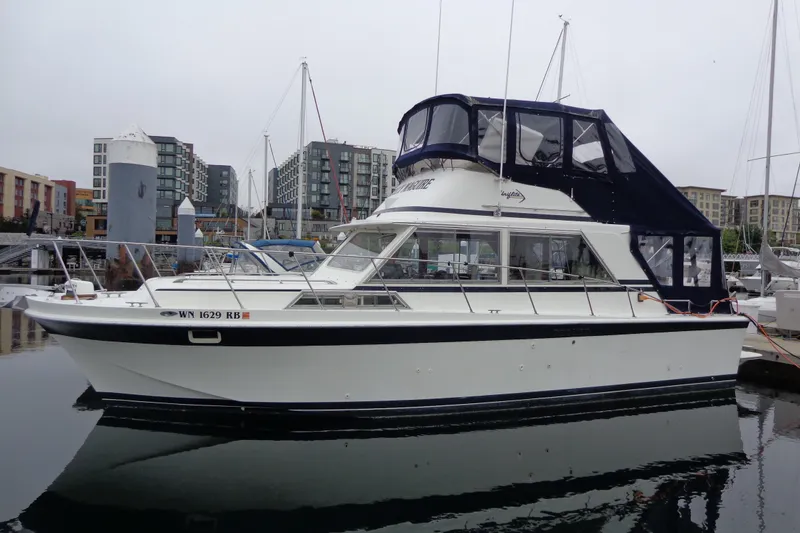 Slide: The Image of 1975 Uniflite Flybridge Sport Sedan docked in a marina, surrounded by modern buildings. - 4