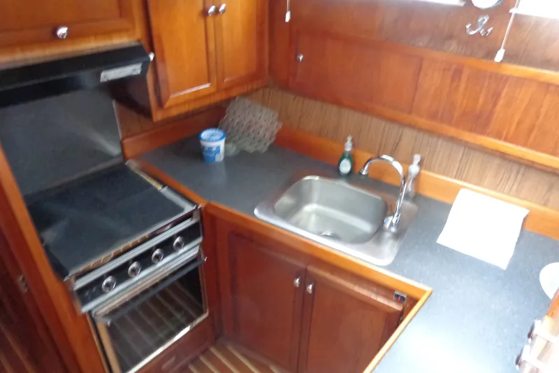 Slide: The Image of 1975 Uniflite Flybridge Sport Sedan kitchen with stove, sink, and wooden cabinetry. - 11