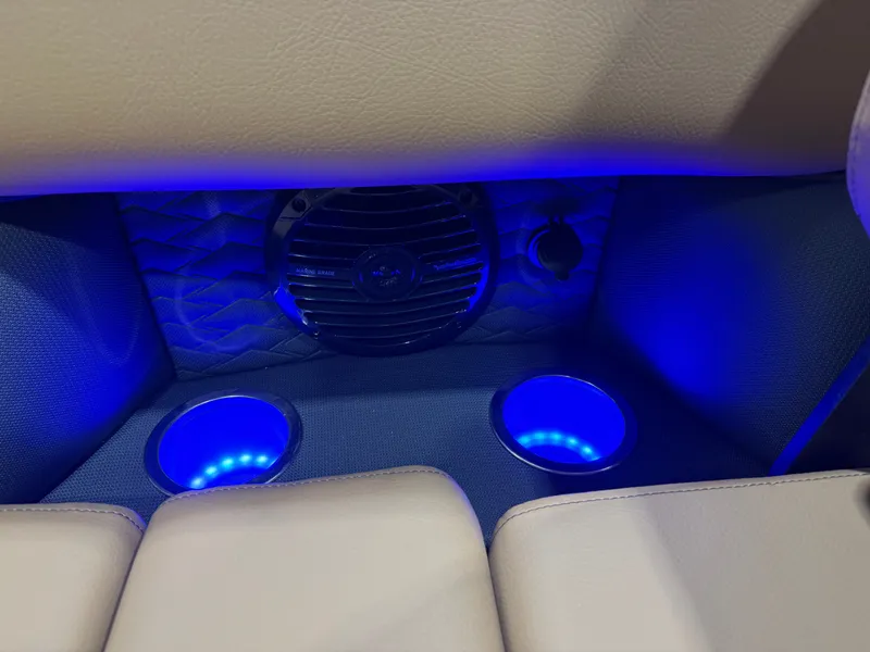 Slide: The Image of The interior of the Bentley Pontoons Elite 223 Swingback Tritoon features illuminated cup holders and a speaker. - 30