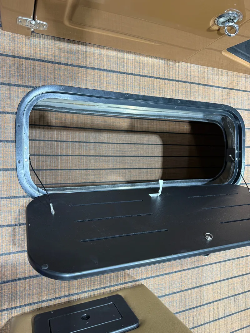 Slide: The Image of An open storage compartment on a boat with a black lid and striped flooring. - 36