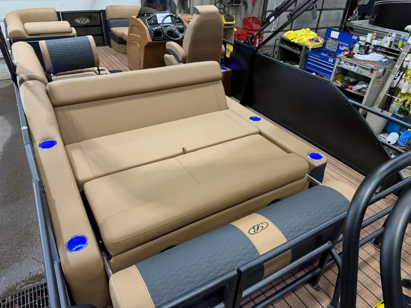 Slide: The Image of The image shows the interior of a Bentley Pontoons Elite 223 Swingback Tritoon with beige leather seating and blue cup holders. - 27