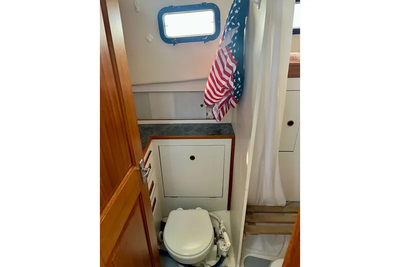 Slide: The Image of 1993 Atlantic Boat Flye Point 32 bathroom with toilet, cabinet, and American flag. - 17