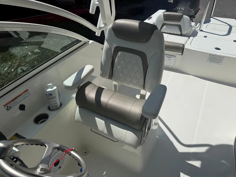 Slide: The Image of A modern boat seat with padded armrests and a sleek steering wheel in a World Cat 230 DC. - 7