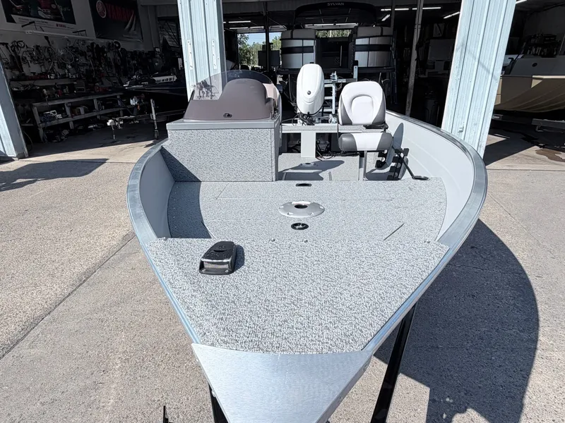Slide: The Image of The image shows a 2027 Starcraft 16 Patriot DLX SC boat. It has a gray deck and is in a workshop. - 21