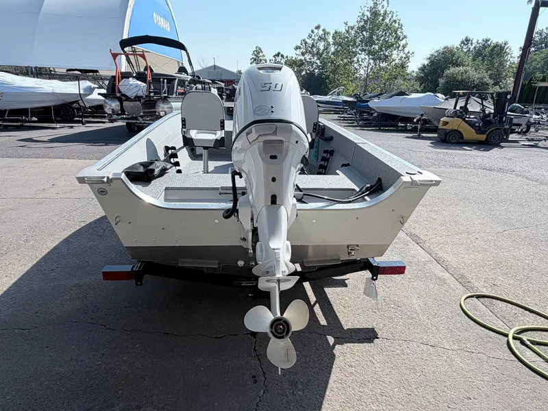 Slide: The Image of A 2027 Starcraft 16 Patriot DLX SC boat with an outboard motor, parked on a trailer. - 16