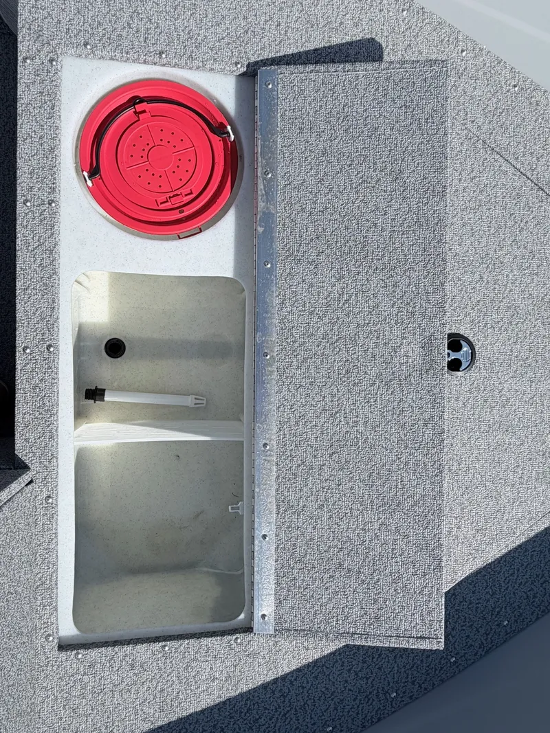 Slide: The Image of An open storage compartment on a boat with a red lid and gray carpeted flooring. - 30