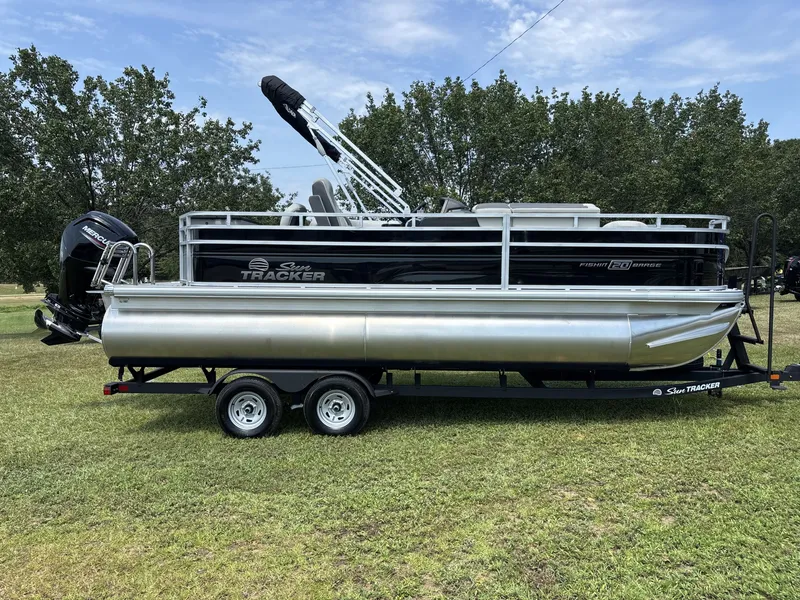 The Image of A 2026 Sun Tracker Fishin' Barge 20 DLX on a trailer, set on a grassy field. - 1