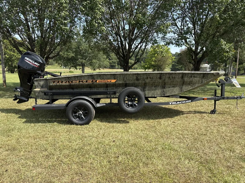 The Image of A 2026 Tracker Grizzly 1756 T Marsh boat on a trailer, surrounded by trees on a grassy field. - 1