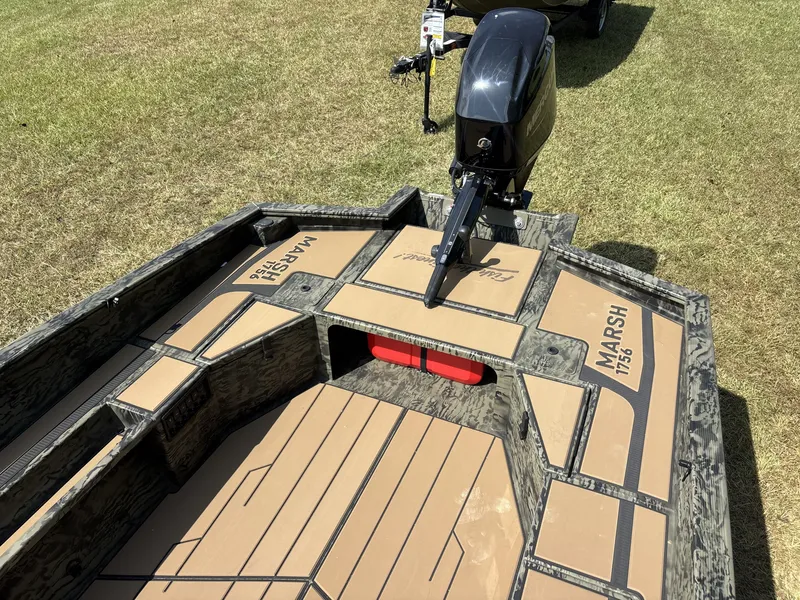 Slide: The Image of The image shows the deck of a Tracker Grizzly 1756 T Marsh boat with an outboard motor. - 14
