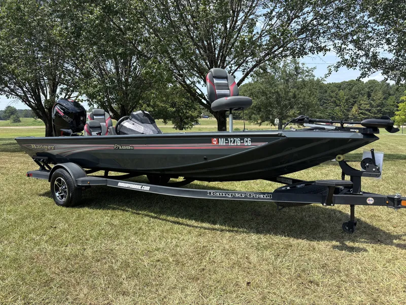 Slide: The Image of A 2025 Ranger RT RT188C boat on a trailer in a grassy area, surrounded by trees. - 2