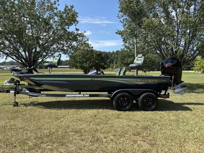 The Image of A 2027 Ranger RT RT198P boat on a trailer in a grassy area, surrounded by trees. - 1