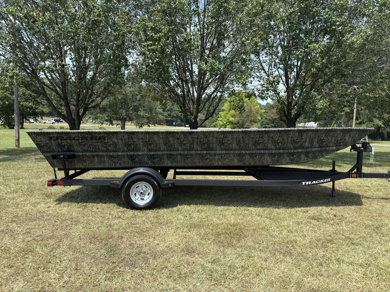 The Image of A 2026 Tracker Grizzly 2072 Utility boat on a trailer, surrounded by trees on a grassy field. - 1