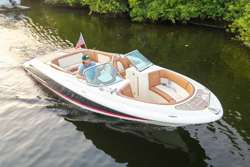 Slide: The Image of 2018 Chris-Craft Launch 27 boat cruising on a calm river with lush greenery. - 34