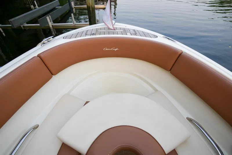 Slide: The Image of 2018 Chris-Craft Launch 27 boat interior with brown and white seating, docked by the water. - 32