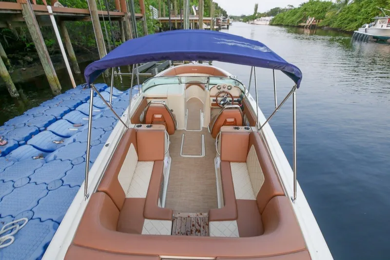 Slide: The Image of 2018 Chris-Craft Launch 27 boat with blue canopy and luxurious seating on a calm waterway. - 5