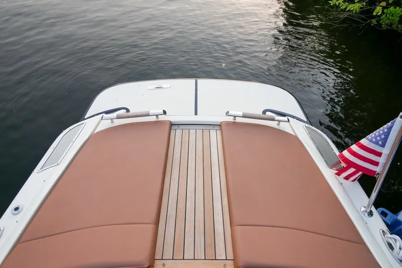 Slide: The Image of 2018 Chris-Craft Launch 27 boat deck with American flag, docked on calm water. - 8