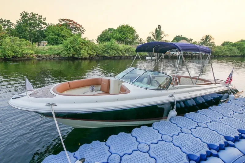 Slide: The Image of 2018 Chris-Craft Launch 27 boat docked on a serene river with lush greenery. - 4