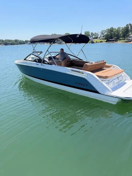 The Image of A 2027 Cobalt R26 boat on a calm lake with a black sunshade. - 1