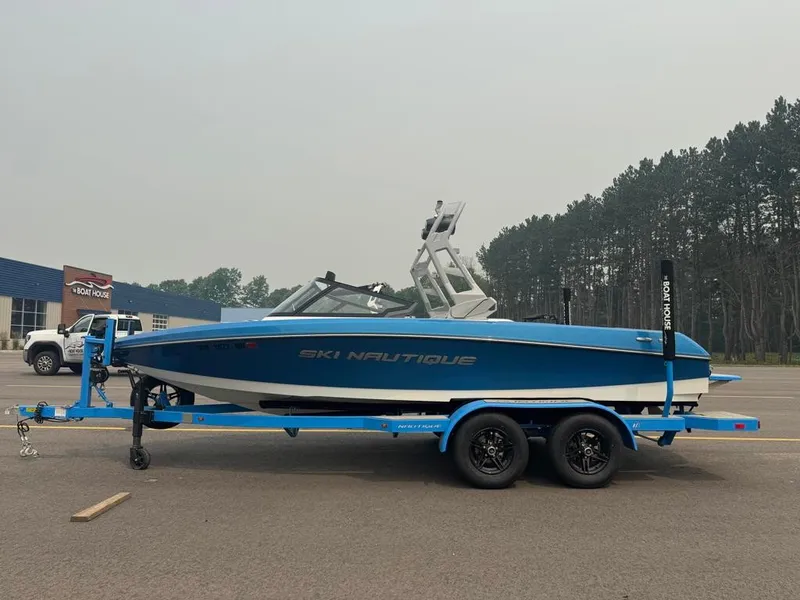 Slide: The Image of A blue 2025 Ski Nautique 200 Open Bow boat on a trailer in a parking lot. - 2