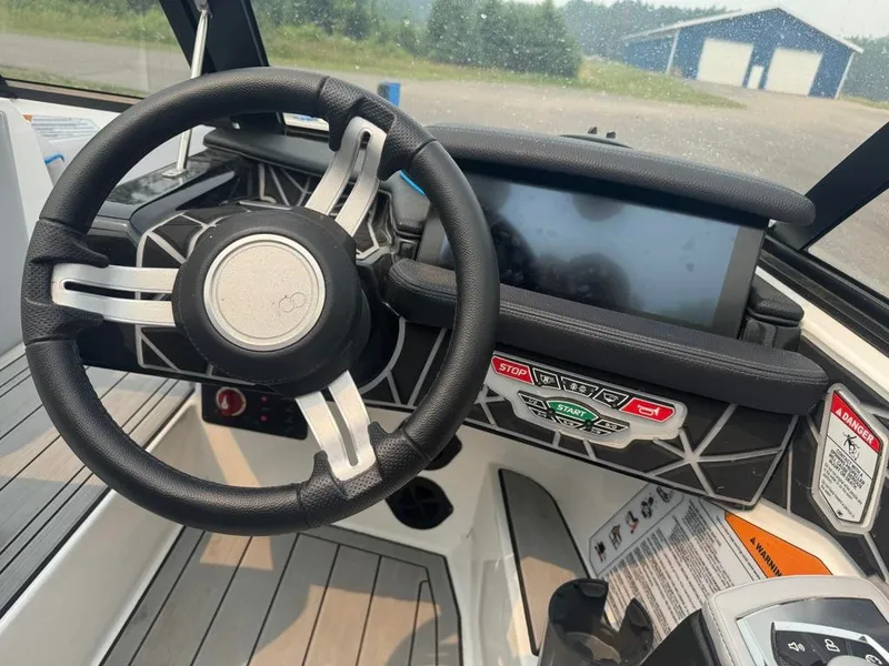 Slide: The Image of The image shows the cockpit of a 2025 Nautique Ski Nautique 200 Open Bow with a modern steering wheel and large display. - 27