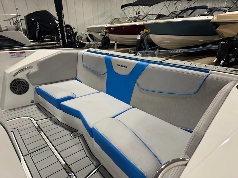 Slide: The Image of The image shows the interior of a 2025 Nautique Ski Nautique 200 Open Bow. The seats are gray with blue accents. - 22