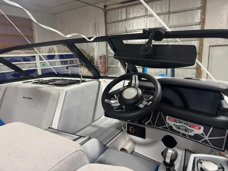 Slide: The Image of The image shows the cockpit of a 2025 Nautique Ski Nautique 200 Open Bow with a modern steering wheel and dashboard. - 19