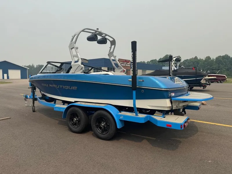 Slide: The Image of A blue 2025 Nautique Ski Nautique 200 Open Bow on a trailer in a parking lot. - 5