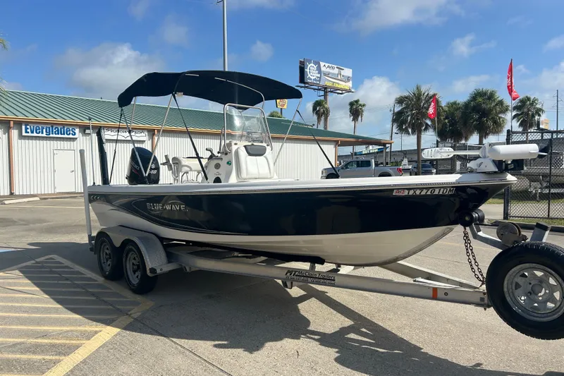 Slide: The Image of 2016 Blue Wave 2000 PureBay boat on trailer, parked outdoors under clear sky. - 3
