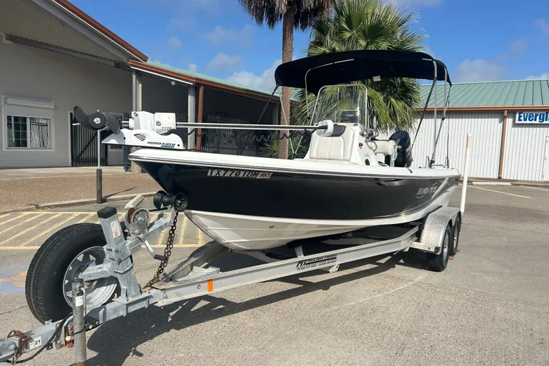 Slide: The Image of 2016 Blue Wave 2000 PureBay boat on trailer, parked outdoors near a building. - 2