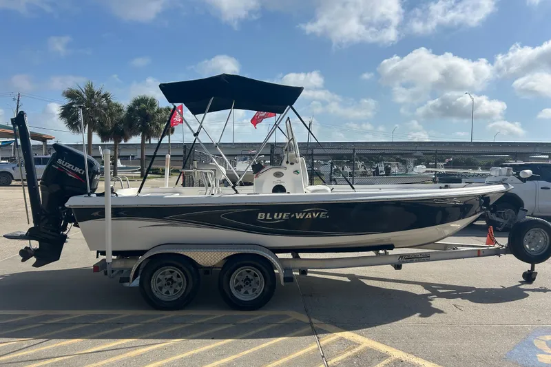 Slide: The Image of 2016 Blue Wave 2000 PureBay boat on trailer, parked outdoors under a clear sky. - 4