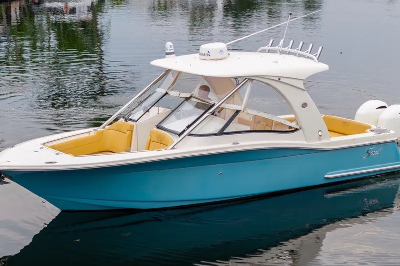 The Image of 2015 Scout 275 Dorado boat with blue hull and yellow seating on calm water. - 0