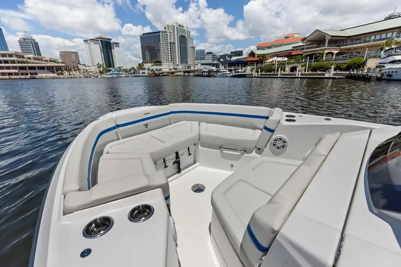 Slide: The Image of The image shows the bow of a Wellcraft 28 Explorer boat with white seating and blue accents. A cityscape with tall buildings is visible in the background. - 34