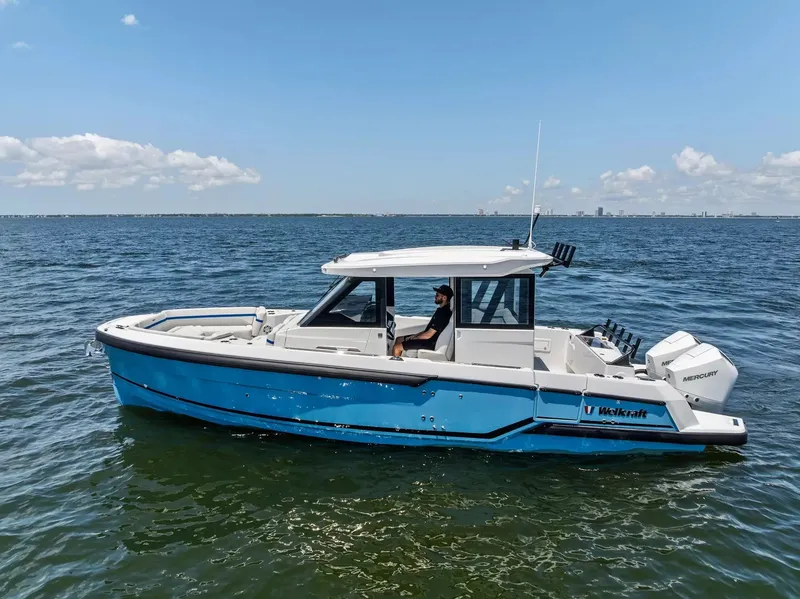 Slide: The Image of A 2027 Wellcraft 28 Explorer cruising on calm waters. It features a blue and white design. - 4