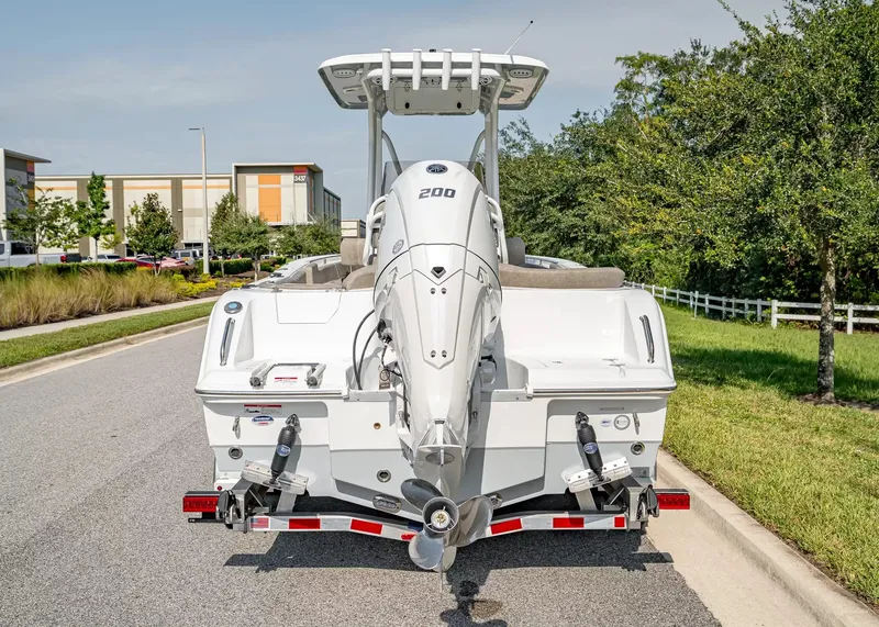 Slide: The Image of A 2027 Sea Hunt Ultra 229 boat on a trailer, parked on a street with trees. - 3