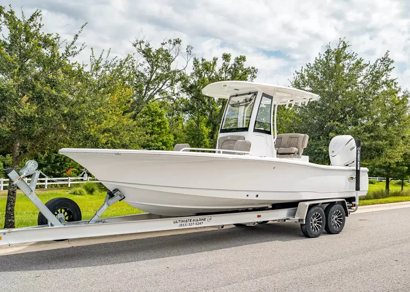 The Image of A 2027 Sea Hunt BX25FS boat on a trailer, surrounded by trees and a cloudy sky. - 1